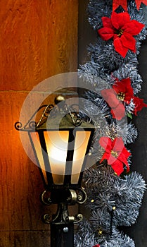 Christmas decoration with a brass lantern illuminating a stone wall and red Poinsettia flowers. Christmas concept. Christmas