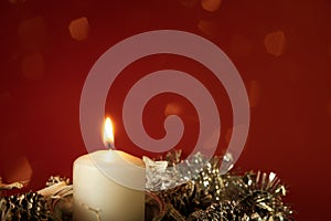 Christmas decoration with a burning candle on red background