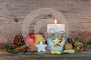 Christmas decoration with candle light, star cookie, red apple, nuts and aromatic spices
