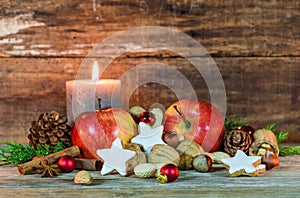 Christmas decoration with candle light, star cookies, red apples, nuts and spices