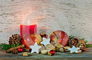 Christmas decoration with candle light, star cookies, red apples, nuts and spices