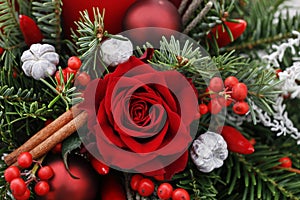 Christmas decoration with candle, red roses, fir, brunia and cinnamon sticks