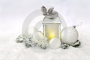 Christmas decoration. Christmas lantern, white balls, cones, white openwork flowers, twigs christmas tree on snow, covered snow