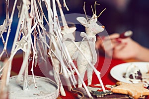 Christmas decoration concept. Vintage toy - christmas deer - with bow on its neck standing over white christmas tree in restaurant