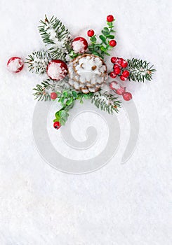 Christmas decoration. Cone pine, twigs christmas tree, red berries, red balls on snow with space for text. Top view, flat lay