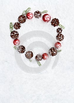 Christmas decoration. Cones pine, christmas toys and branch christmas tree on snow. Top view, flat lay