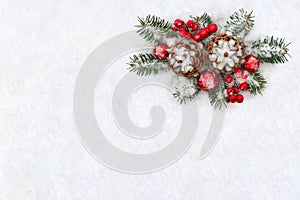 Christmas decoration. Cones pine, twigs christmas tree, red balls, red berries on snow with space for text. Top view, flat lay