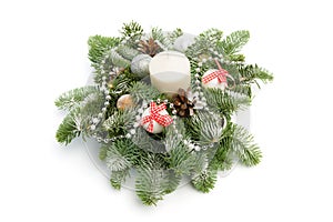 Christmas decoration consisting of fir twigs, shiny balls, cones around the candle, covered with snow on a white background