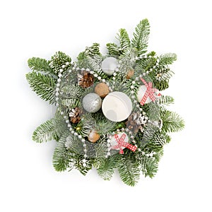 Christmas decoration consisting of fir twigs, shiny balls, cones around the candle, covered with snow on a white background
