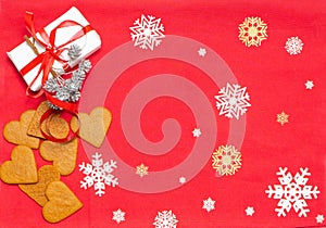 Christmas decoration, cookies and gift box on the red background with snowflakes.