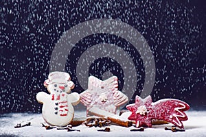 Christmas decoration and cookies.Woman hand sprinkling sugar on a cookies. Flour and spices for a baking on a dark backg