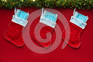 Christmas decoration with Coronavirus on a red background, christmas socks, face masks and hydroalcoholic gels. Covid concept on