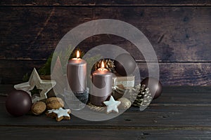 Christmas decoration in dark rose and brown with candles balls, cones and stars agains a rustic wooden background, copy space,