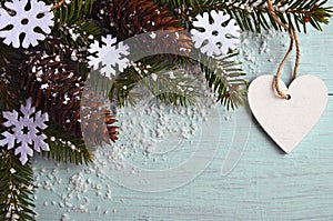 Christmas decoration.Decorative snowflakes,fir cones,heart and snowy fir tree branch on light blue background with copyspace photo