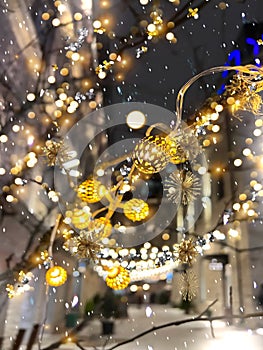 Christmas decoration on evening street gold confetti, snowflakes guirlande and blurred light in Tallinn old town