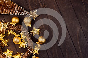 Christmas decoration - fir, glossy and glitter balls, wreath, golden stars on lights garland glowing on dark rich brown plank.