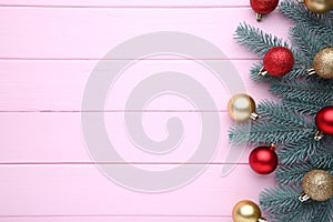 Christmas decoration. Fir-tree branch with balls, bows on a pink background