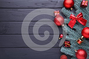 Christmas decoration. Fir-tree branch with balls, little gifts and bows on a black background