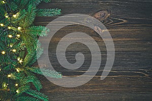 Christmas decoration. Fir tree and christmas lights on rustic, wooden background.