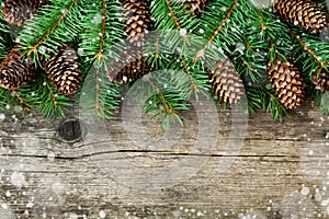 Christmas decoration of fir tree and conifer cone on textured wood background, magic snow effect