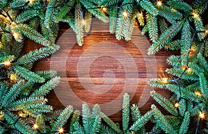 Christmas decoration. Fir tree frame witch christmas lights on rustic, wooden background.