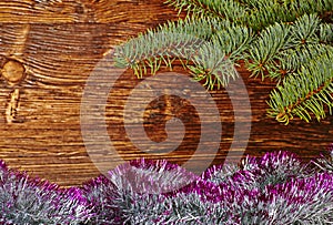 Christmas decoration. Fir-tree, tinsel and wooden background.