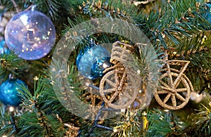 Christmas decoration in the form of a bicycle with golden sparkles on a Christmas tree with a garland