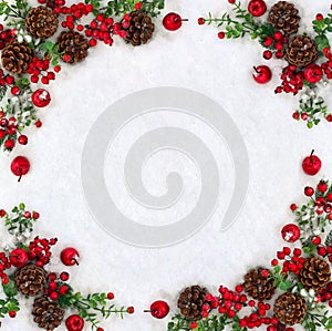 Christmas decoration. Frame of cones pine, twigs christmas tree, red berries and apples on snow with space for text.