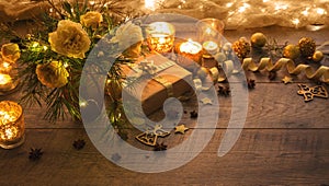 Christmas decoration. Gift, candles, lights, golden balls on a wooden rustic table. Composition of pine branches and