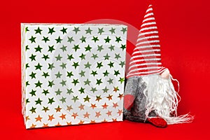 Christmas decoration with a gnome and a gift box on red background