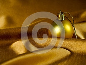 Christmas decoration on gold background, Golden balls and silk fabric. Christmas card, space for text. The decor for the new year