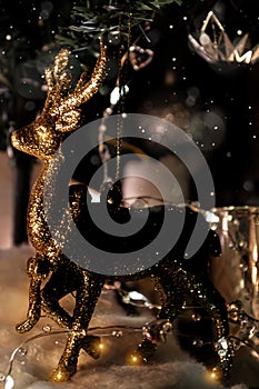 Christmas decoration golden shiny deer on dark background with candle lantern and fir branch