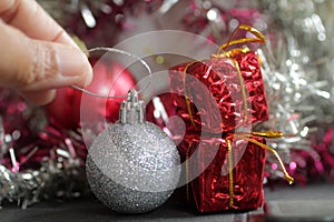 Christmas decoration. Hand of person holding white ball Christmas ornament with red ball and red presents background.