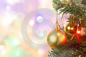 Christmas decoration. Hanging gold balls on pine branches Christmas tree garland and ornaments over abstract bokeh background with