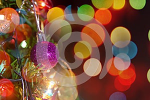 Christmas decoration. Hanging purple balls on pine branches christmas tree garland and ornaments over abstract bokeh background