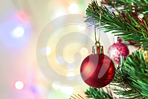 Christmas decoration. Hanging red balls on pine branches Christmas tree garland and ornaments over abstract bokeh background with
