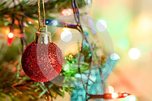 Christmas decoration. Hanging red glitter balls on pine branches Christmas tree garland and ornaments over abstract bokeh