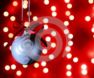 Christmas decoration hanging from a string in front of festive lights blurred out to create bokeh