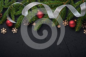 Christmas Decoration. Holiday Decorations with baubles, fir branches and present on dark black background. Border design. Top view