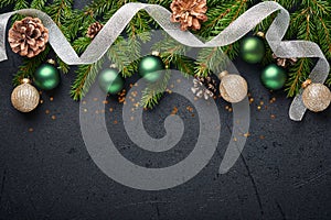 Christmas Decoration. Holiday Decorations with baubles, fir branches and present on dark black background. Border design. Top view