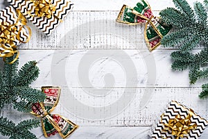 Christmas Decoration. Holiday Decorations with gold baubles, cones, bells, fir branches and present on the old white wooden board