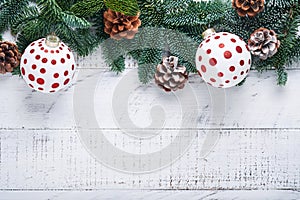 Christmas Decoration. Holiday Decorations with gold baubles, cones, bells, fir branches and present on the old white wooden board