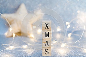 Christmas decoration on a light blue glittered background with wooden cubes forming word Christmas