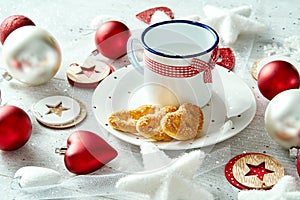 Christmas decoration with milk plate with gingerbreads snowflakes and baubles on a white table.