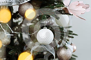 Christmas Decoration. New year. gentle pastel colors. Pink, silver and white Balls on Christmas tree branch with garland lights.