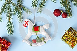Christmas decoration - old rocking horse, fir branches, golden gifts, red Christmas balls on blue background. Concept holidays