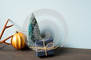 Christmas decoration ornament fir tree, golden ball, deer antler, gift box on wooden table. blue wall background