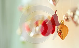 Christmas decoration ornaments. Bell, heart and gloves shape toys hanging on wall with blur gold background.