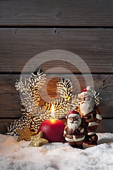 Christmas decoration on pile of snow against wooden wall