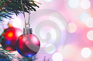 Christmas decoration. Red balls hanging on pine branches christmas tree garland and ornaments over abstract bokeh background with